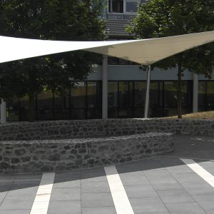 Ein Sonnensegel nach Maß an einem öffentlichen Platz vor einem Gebäude.
