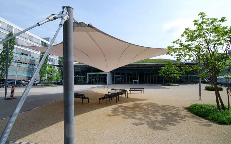 Ein Sonnensegel nach Maß an einem öffentlichen Platz vor einem Gebäude. Ein Sonnensegel nach Maß an einem öffentlichen Platz vor einem Gebäude.